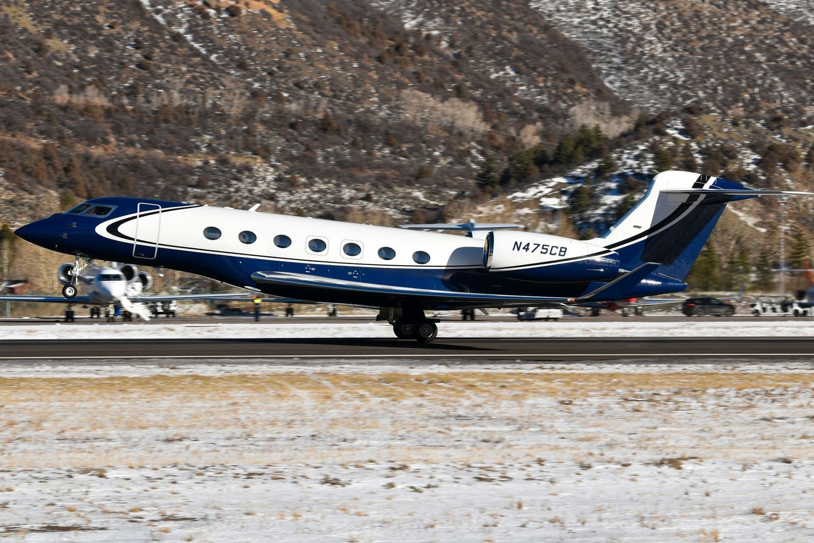 A Gulfstream G600 departing Aspen against a snow-covered hillside