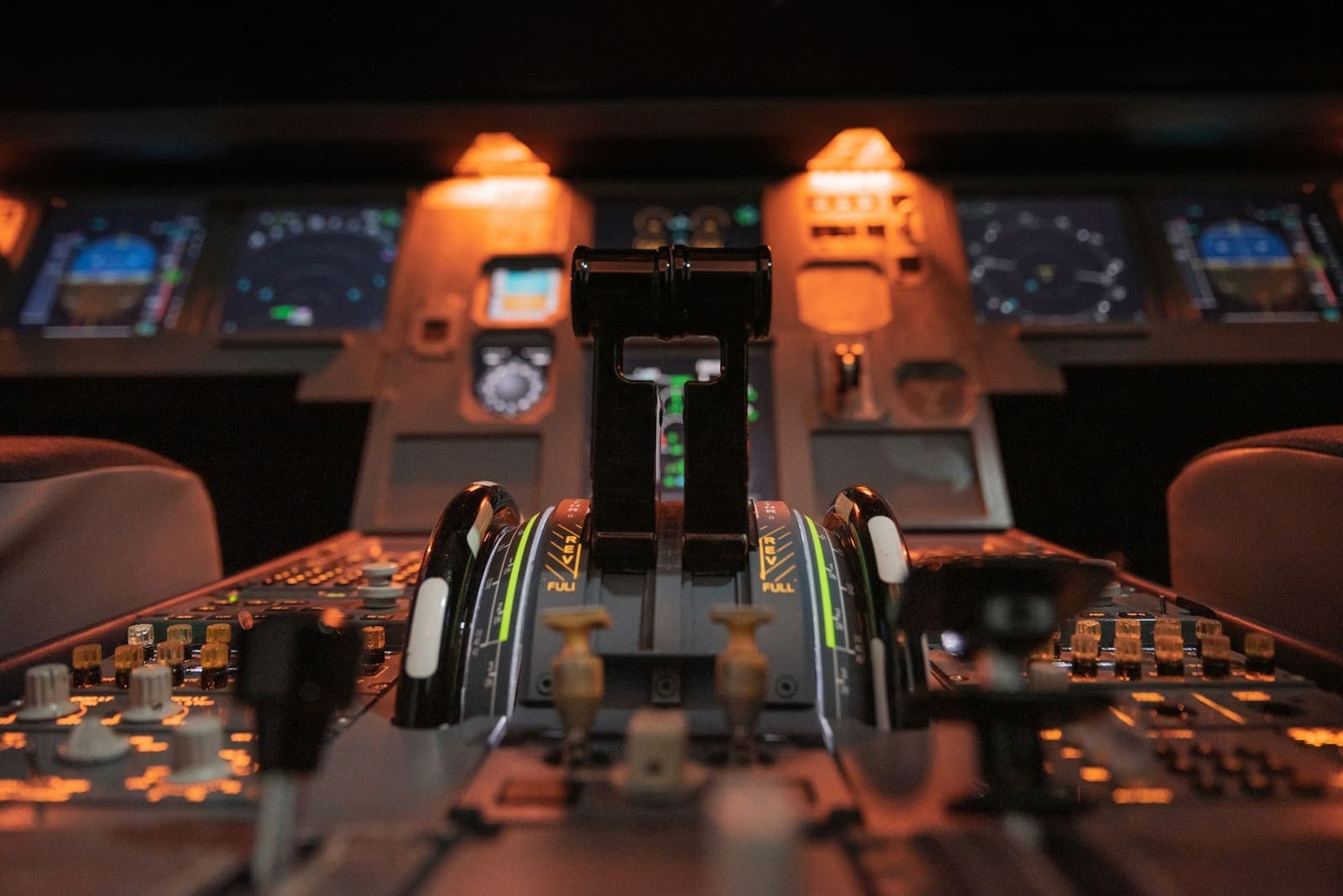 Throttle levers in an aircraft cockpit lit by warm light